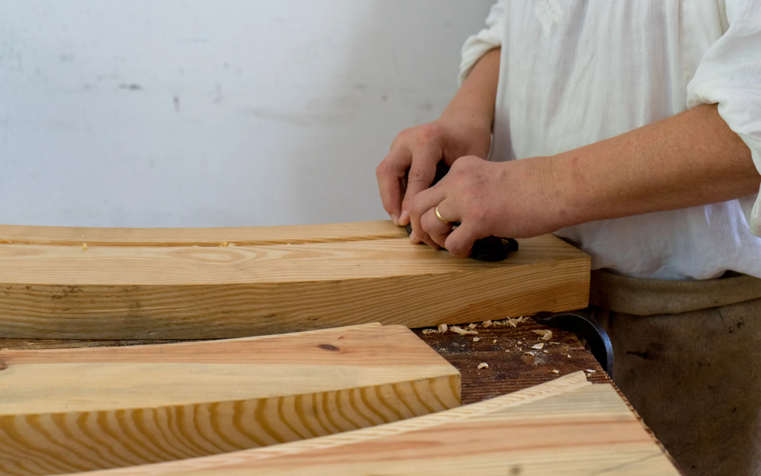 Artisan façonnant des planches de bois massif dans un atelier
